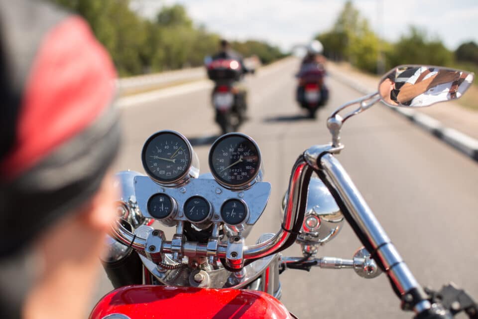 Biker riding motorcycle on road in morning sunny day Shot from behind
